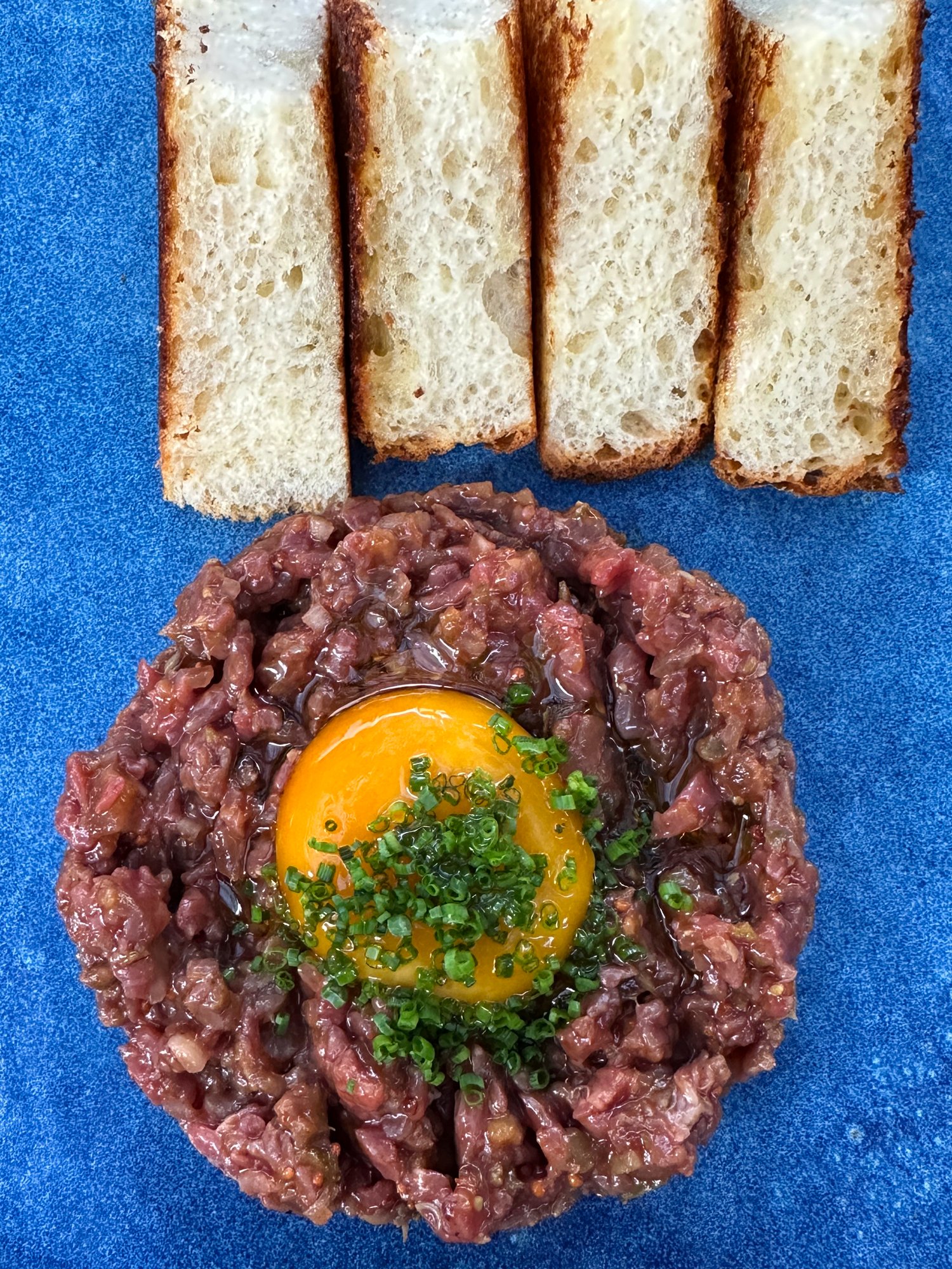 Beef Tartar mit Brot auf blauem Teller