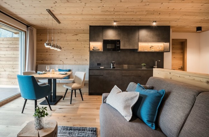 Moderne schwarze Küche und Esszimmer Bereich eines Holzchalets mit stilvollen Stühlen und Kissen