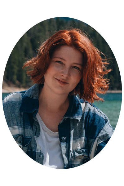 Luise Kenner ist in einem blau-weiß kariertem Hemd vor einer Seelandschaft zu sehen