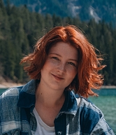 Luise Kenner vom Reiseblog Falubeli posiert vor einem Bergsee, im Hintergrund Tannen.