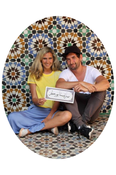 Ein Reiseblogger-Pärchen posiert vor einer bunten Fliesenwand