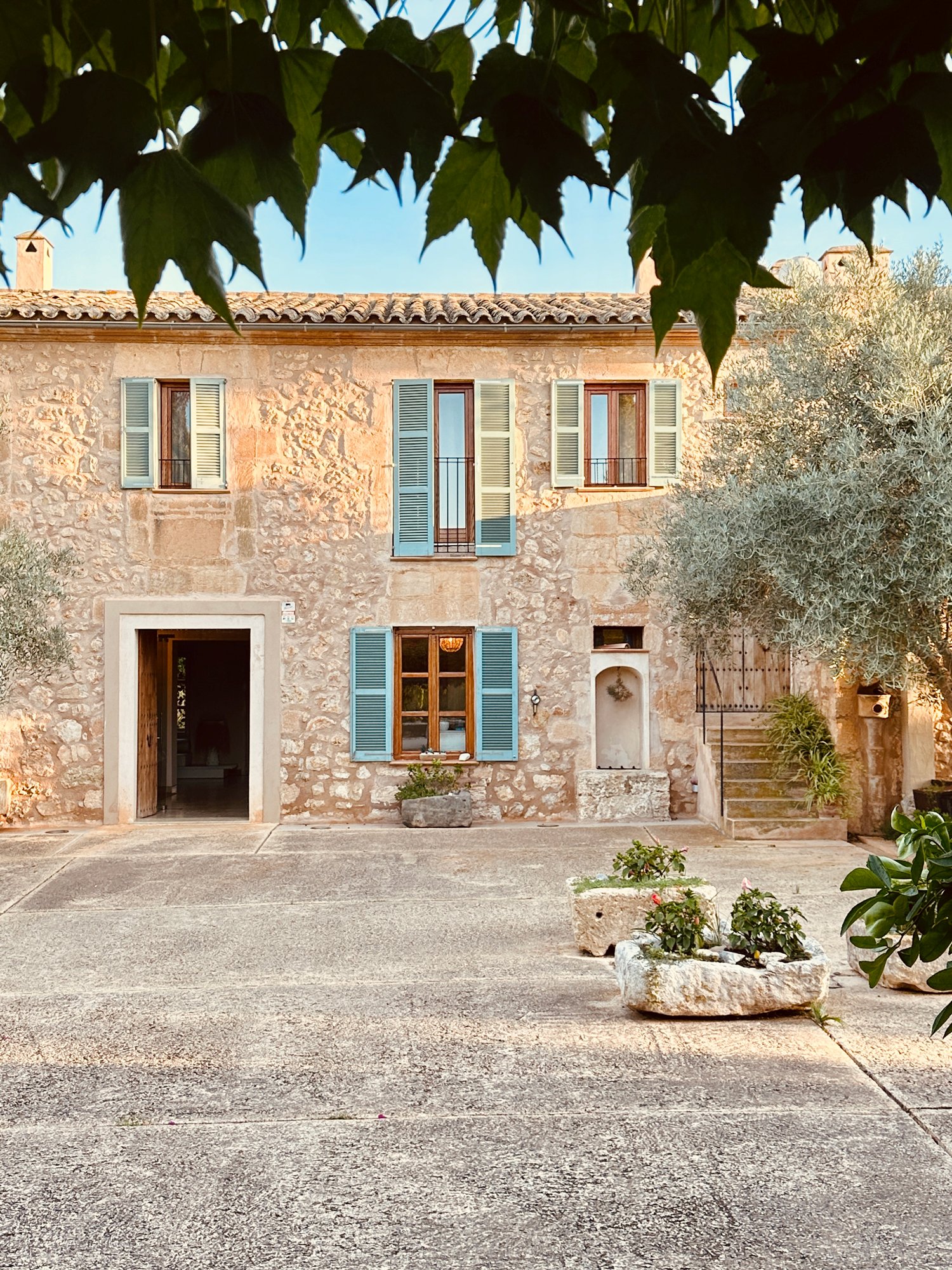 Blick auf die historische Steinfassade des Fincahotels Sa Franquesa Nova, die Fenster sind mit türkisblauen Fensterläden versehen - typisch für die Insel