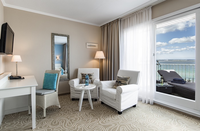 Helles, gemütliches Hotelzimmer mit einigen türkisblauen Akzenten und Blick direkt auf die Ostsee