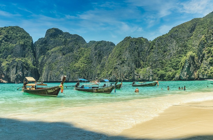 Thailändischer Strand mit Longtail Boot und Insel im Hintergrund
