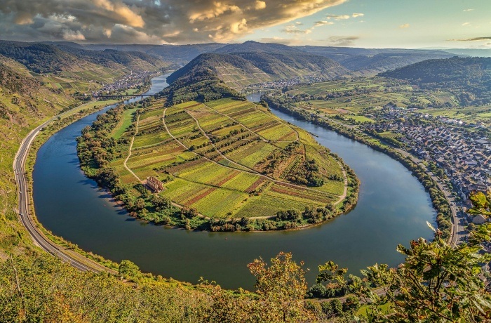 Weingut Hotels in Deutschland: Blick auf eine Flussschleife mit Weinbergen auf der Halbinsel, umgeben von Hügeln und Dörfern im Moseltal.