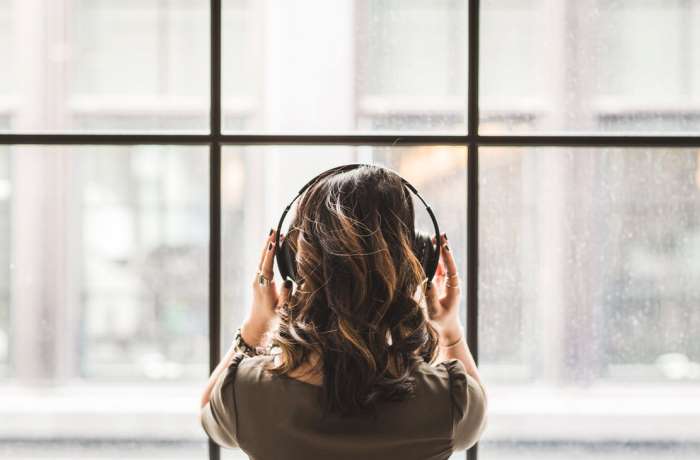Top 15 Reise-Podcasts: Frau mit Kopfhörern schaut aus dem Fenster
