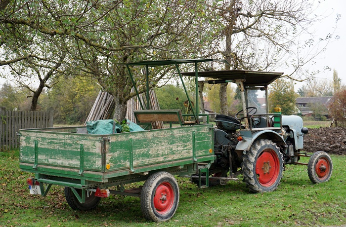 Landwirtschaft wird in Franken noch gelebt, hier ein Traktor in einem Garten unter Bäumen.